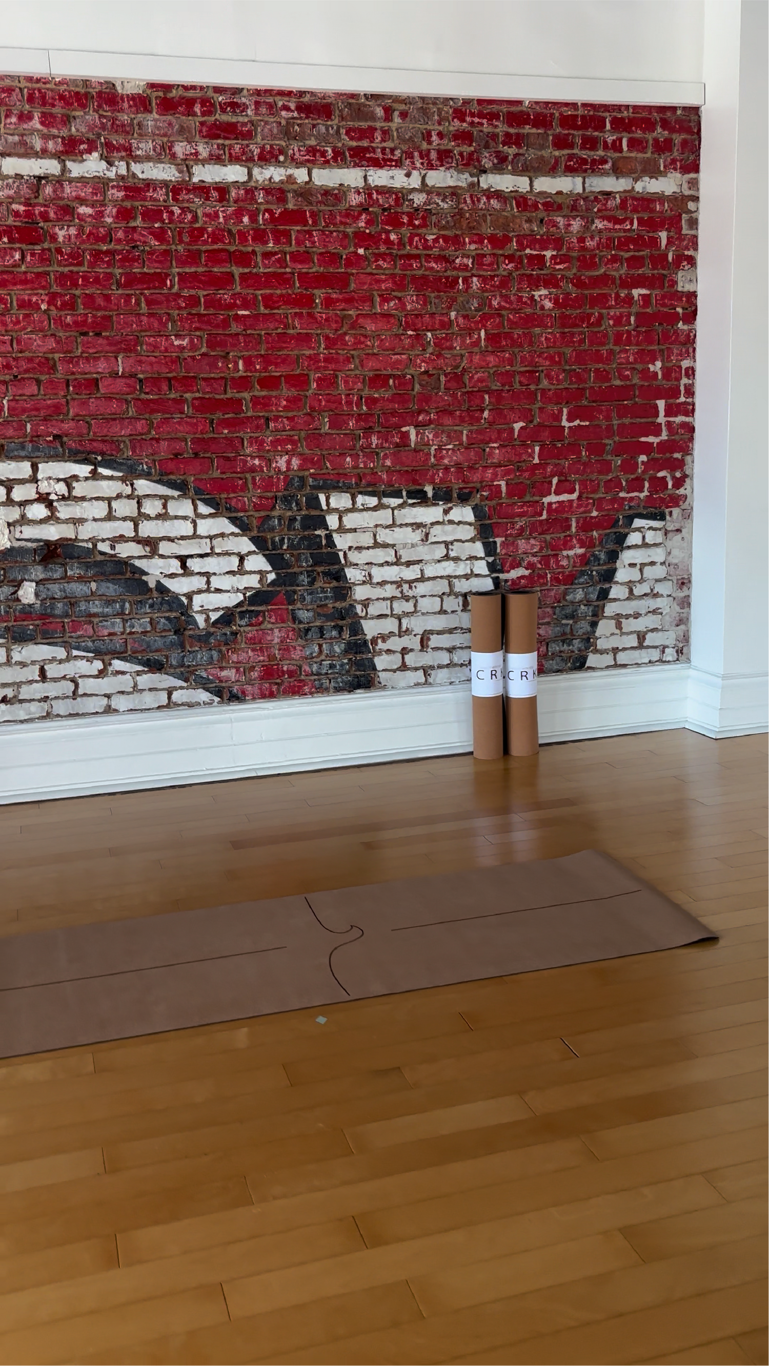 crk yoga mats by a red brick graffiti wall in a yoga studio